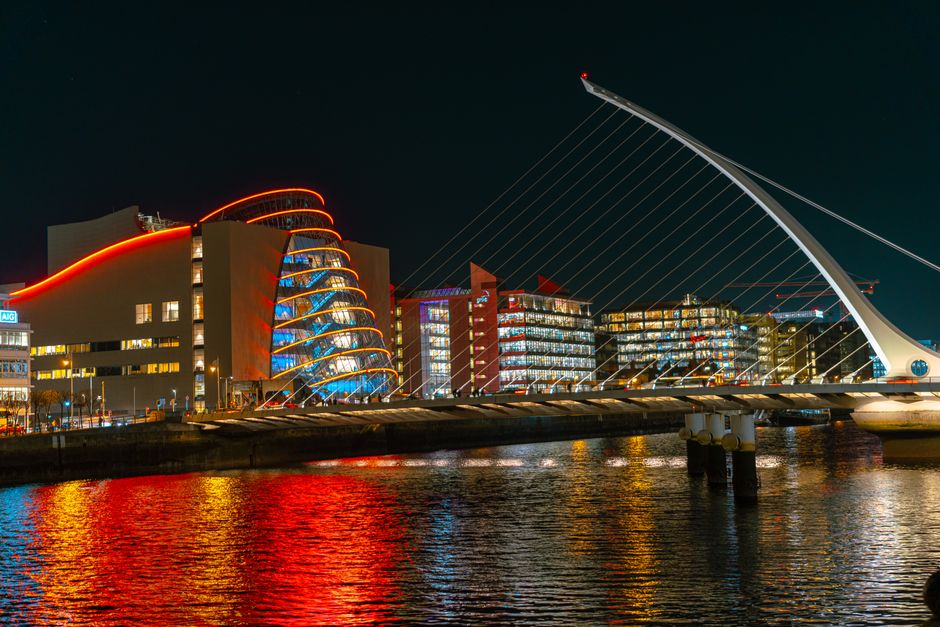 Night view of Dublin Docklands with modern buildings and river reflections.