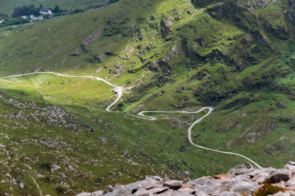 Winding mountain road in Ireland's lush green landscape.