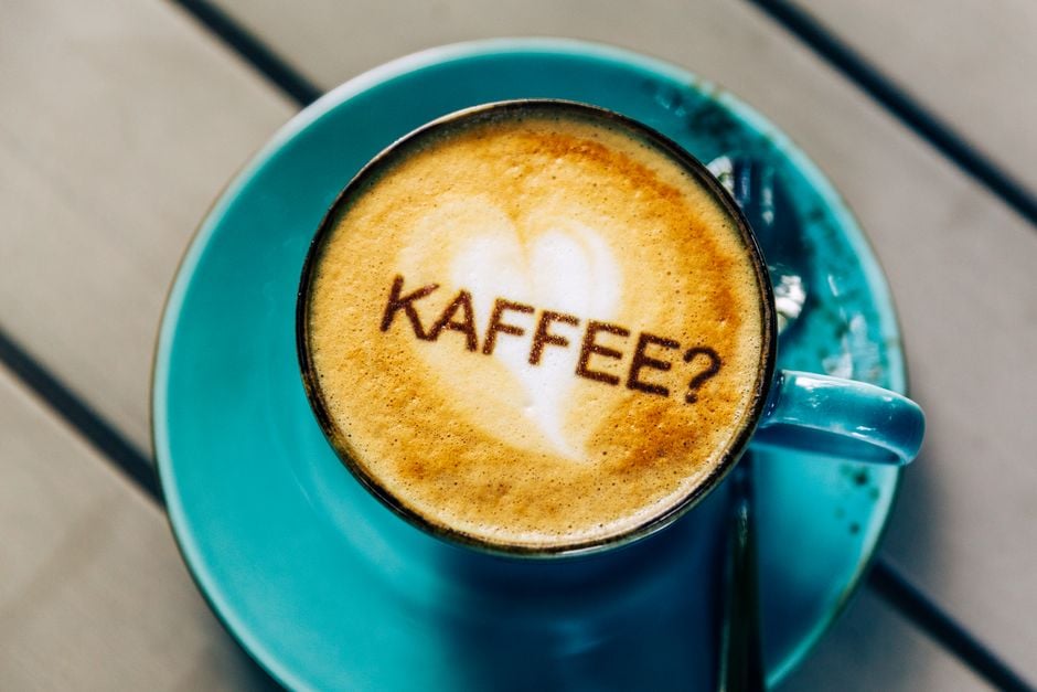Coffee in a blue cup with 'KAFFEE?' written in foam, Galway café scene.