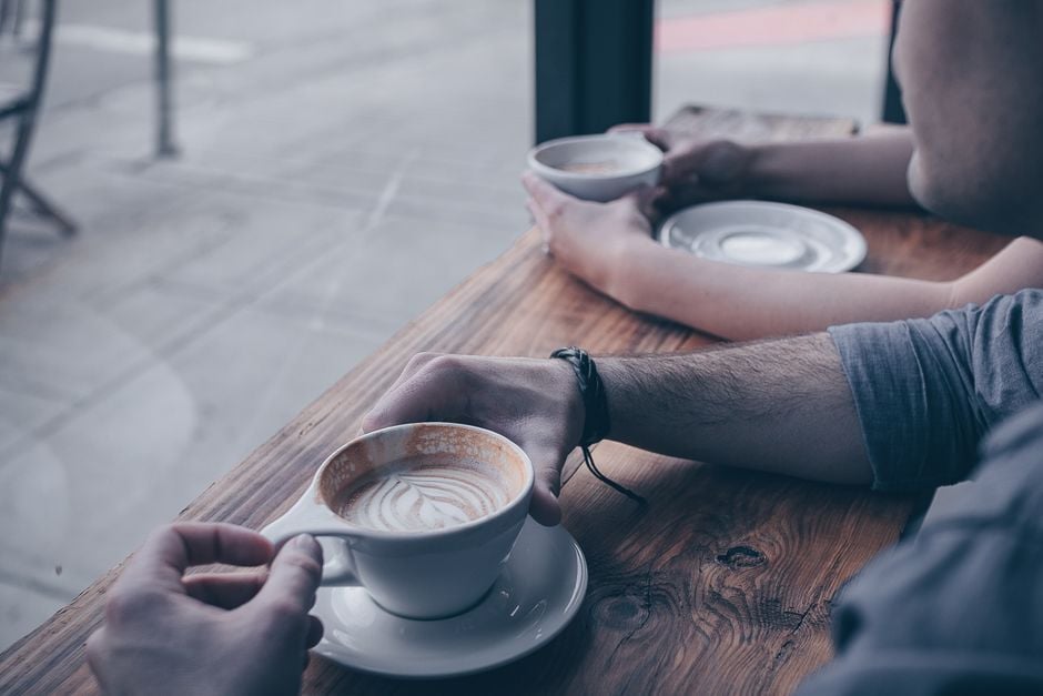 People enjoying coffee at a Galway café with large windows.