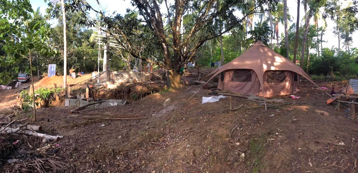 Temporary tent shelter amidst green jungle trees, perfect for eco-travel experiences.