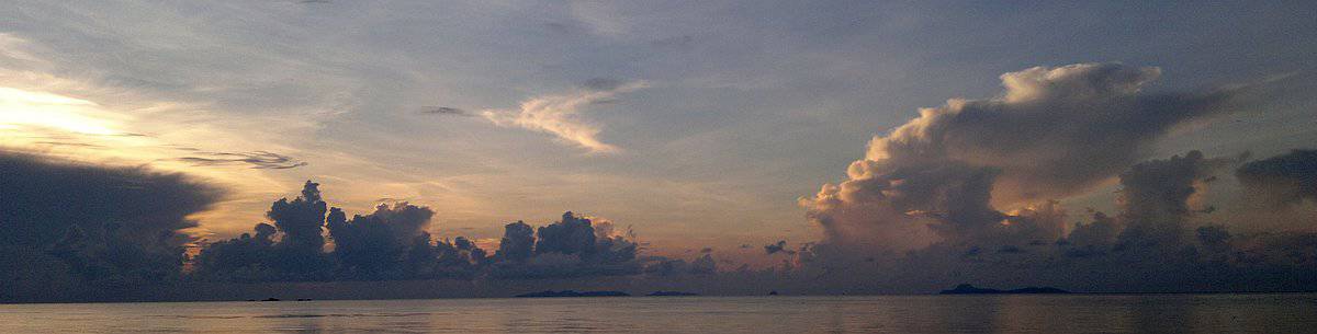 Sunset over a calm ocean with dramatic clouds filling the sky, reflecting soft hues of orange and purple, reminiscent of a stunning Palawan sunrise.