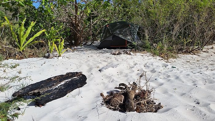 Camping tent set up on white sandy beach surrounded by greenery in the Philippines.