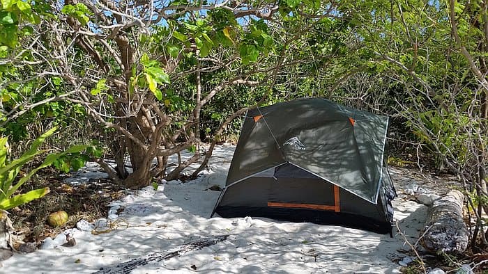 Small tent set up on sandy beach surrounded by lush greenery in the Philippines.