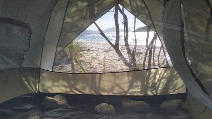 Camping tent with beach view in the Philippines, surrounded by trees and nature.