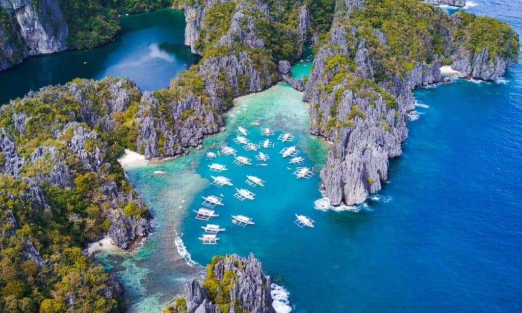 Aerial view of a tropical lagoon in Coron, where boats are nestled among rocky cliffs and lush greenery, perfect for an exhilarating excursion.