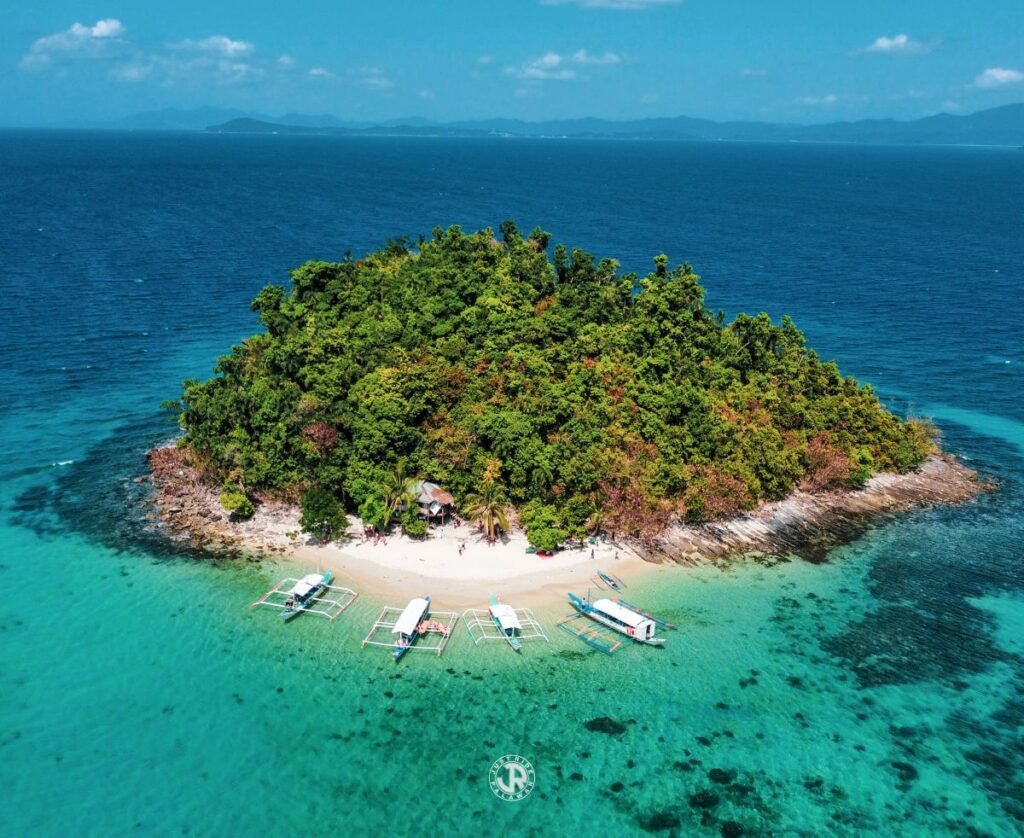 Port Barton island surrounded by turquoise waters with boats and lush greenery.