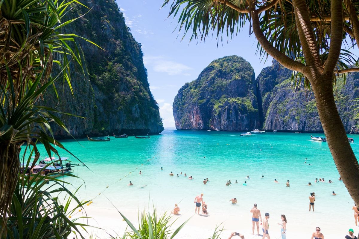 Beach scene with turquoise waters and limestone cliffs.
