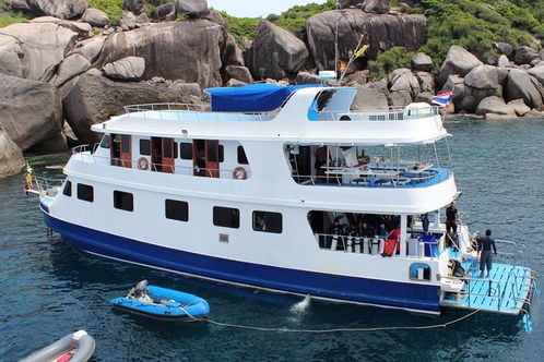 Manta Queen yacht docked near rocky shoreline in Thailand.