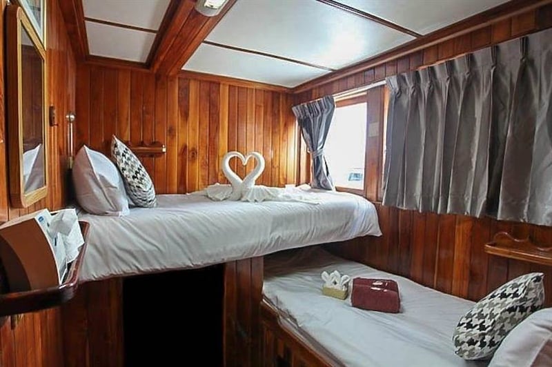 Interior of a cozy wooden cabin on Manta Queen cruise in Thailand.