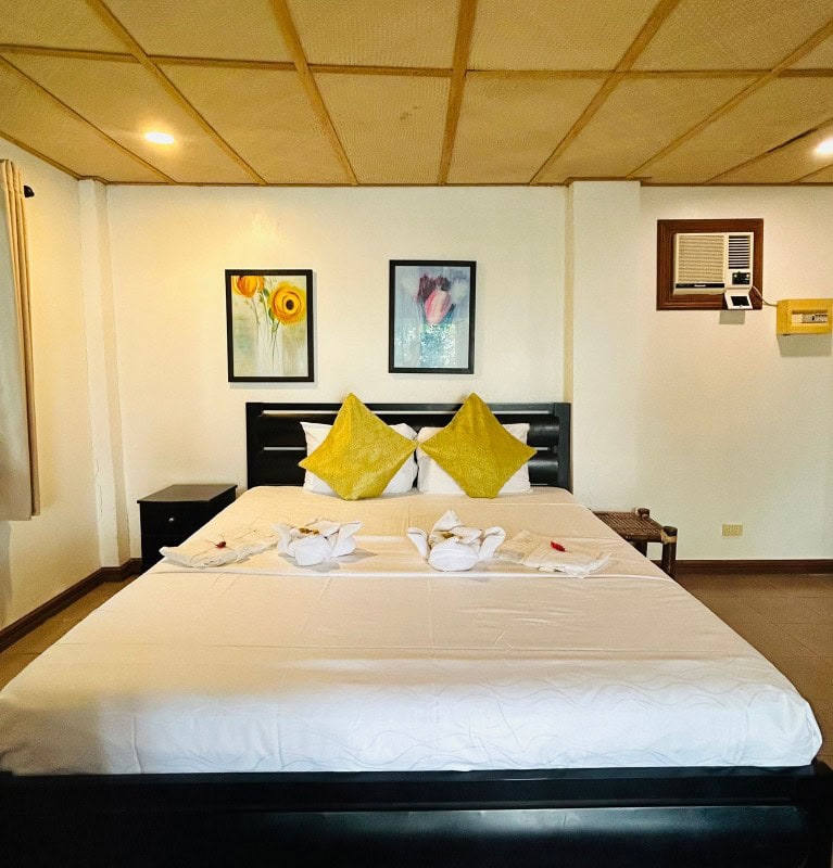 Cozy Philippines hotel room featuring a large bed, colorful pillows, and simple decor for a relaxing stay.