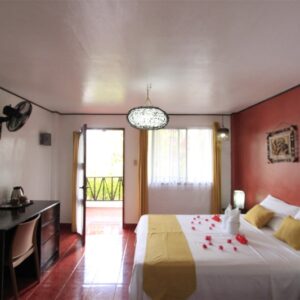 Cozy hotel bedroom with a double bed, yellow accents, and rose petal decor, perfect for a relaxing Philippines getaway.