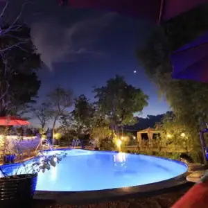 Poolside relaxation under the stars in the Philippines with ambient lighting, lush greenery, and cozy outdoor seating.