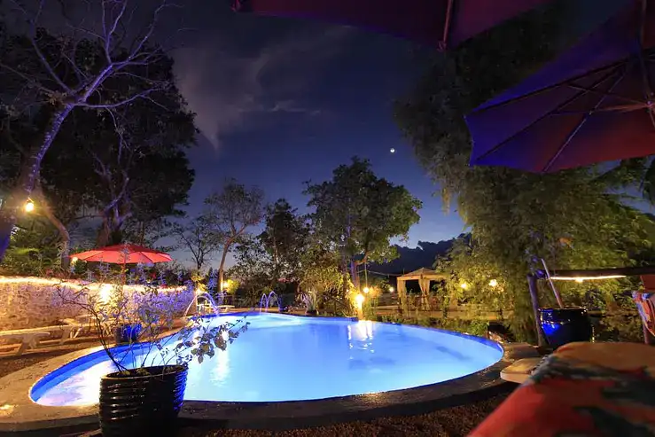 Poolside relaxation under the stars in the Philippines with ambient lighting, lush greenery, and cozy outdoor seating.