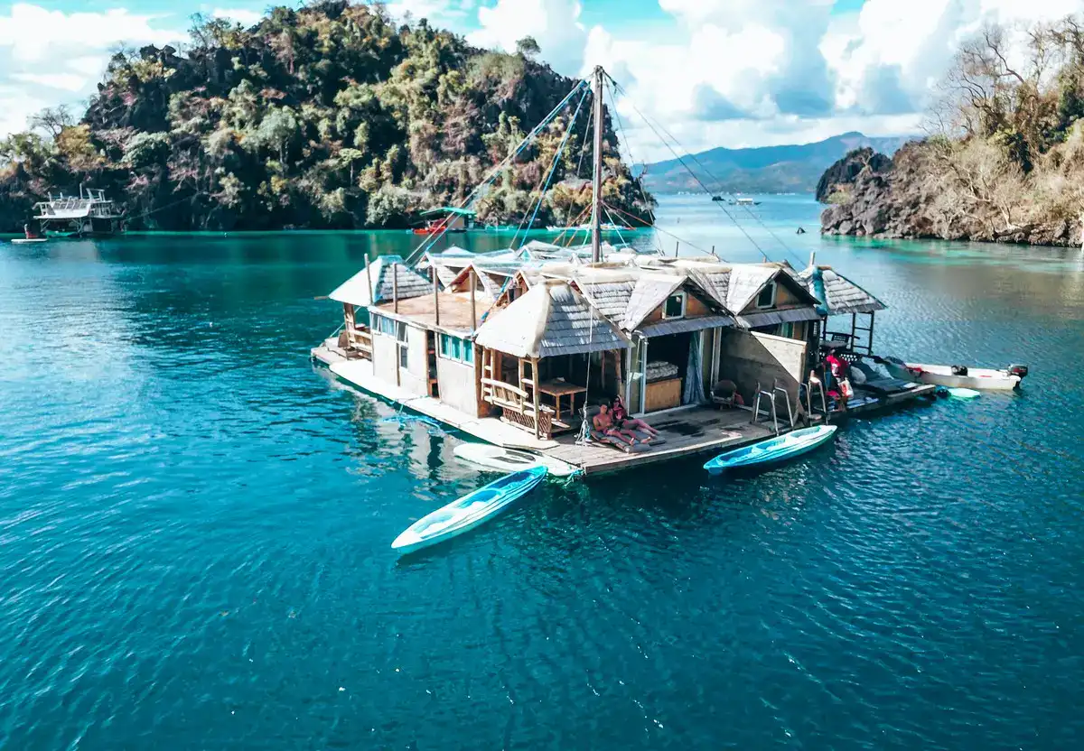 A charming houseboat floating peacefully on clear blue waters near lush island scenery.