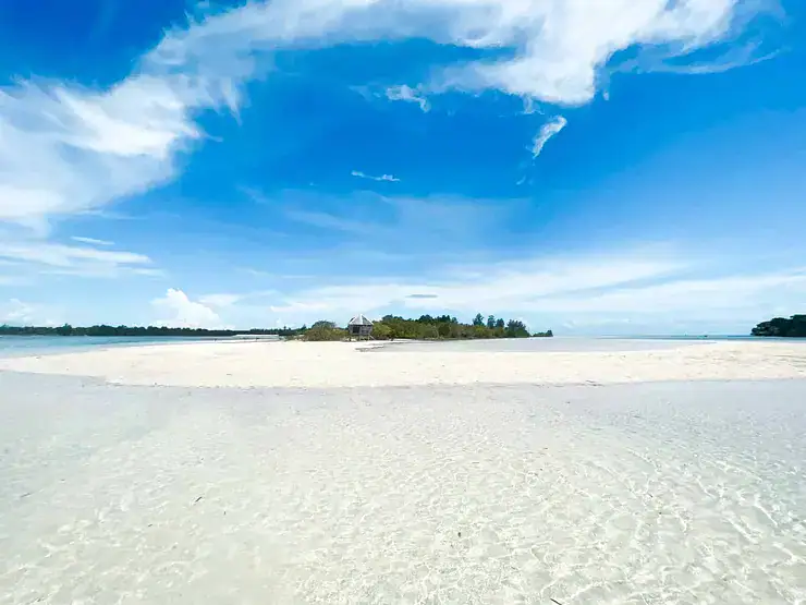 Pristine white sand beach in the Philippines with clear blue skies, perfect for relaxing and island hopping.