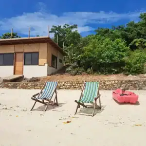Beach house with kayaks and lounge chairs on sandy shore in the Philippines.