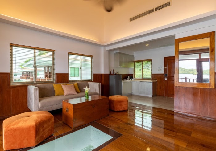 Bright living room with wooden accents, modern furniture, and large windows overlooking nature.