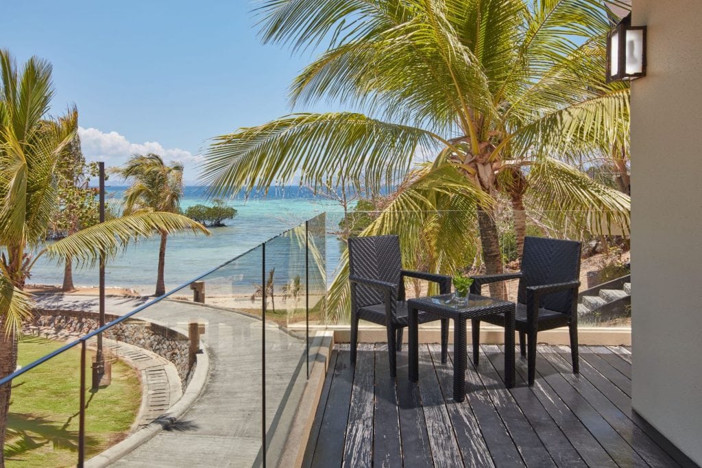 Oceanfront balcony with palm trees and seating in the Philippines.