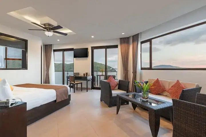 Bright, modern hotel room with ocean views, seating area, and balcony in the Philippines.