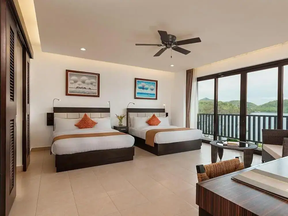 Spacious hotel room in the Philippines with two beds, ocean view balcony, and contemporary decor.