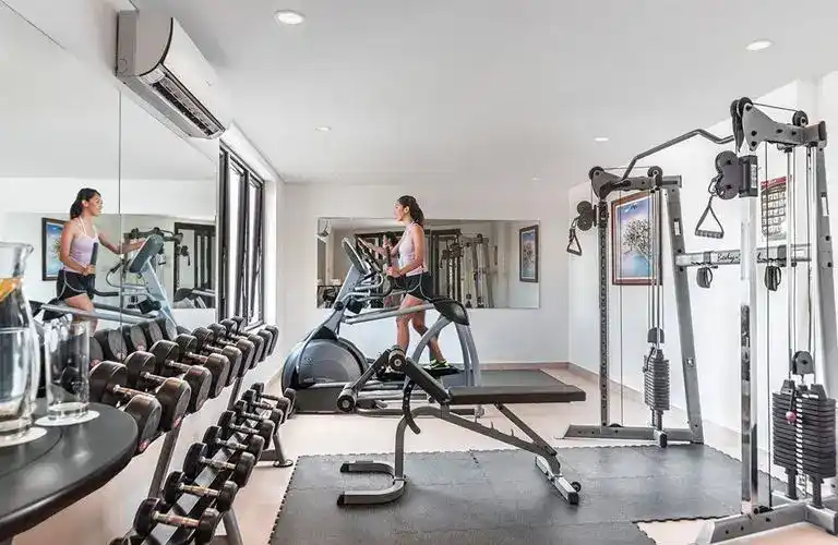 A woman exercising on cardio machines in a bright, well-equipped gym in the Philippines.