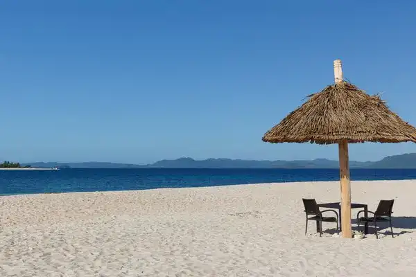 Scenic beach with white sand, straw umbrella, and ocean view in the Philippines.