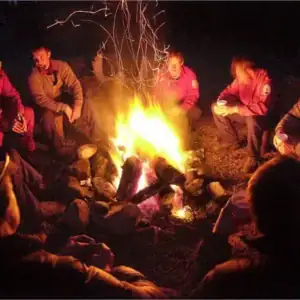 People gathering around a campfire during a night in the Philippines, enjoying outdoor adventure.