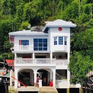 Bright white house built on stilts over the water, surrounded by lush greenery in the Philippines.