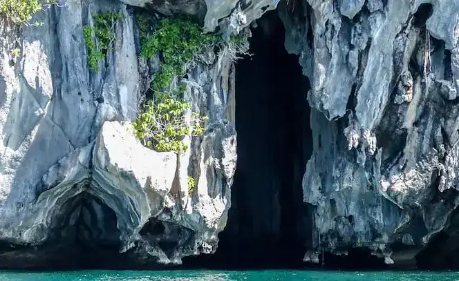 Stunning limestone cave entrance surrounded by blue waters in the Philippines.