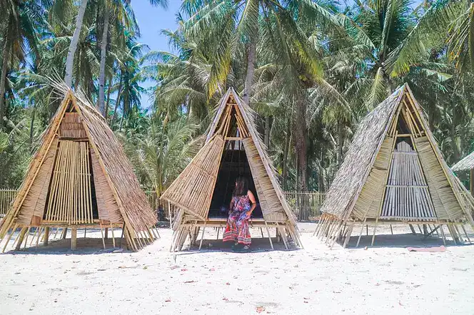 Traditional bamboo huts with palm trees in the background, perfect for island hopping and exploring Philippines.