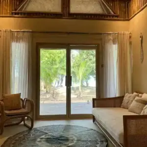 Cozy living room with large glass doors overlooking tropical beach and palm trees in the Philippines.