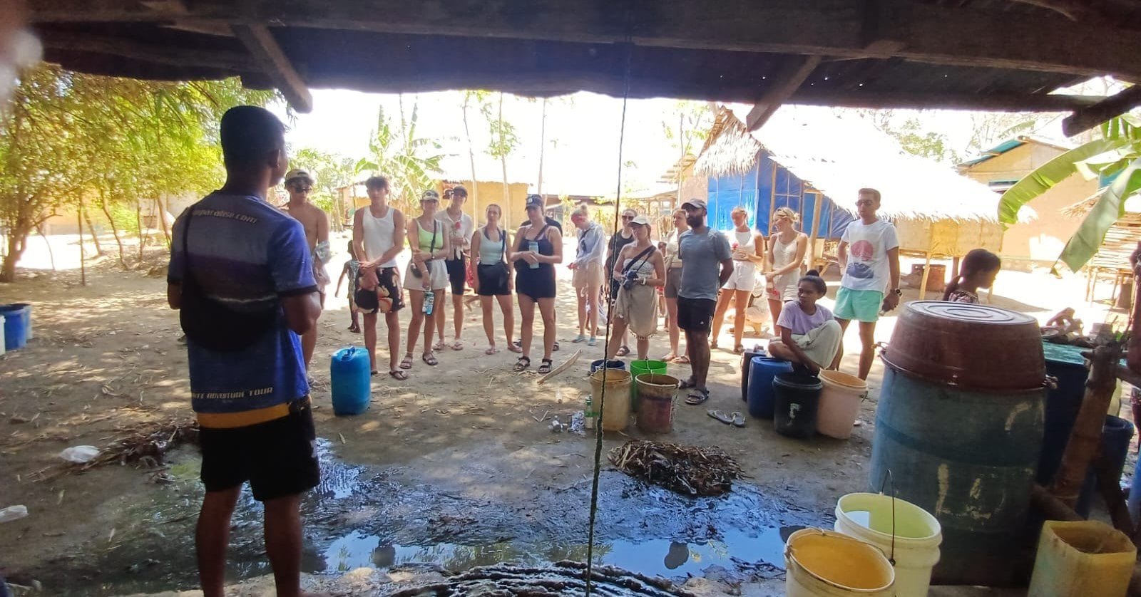 Enhanced SEO ALT: Tour guide explaining Filipino culture to tourists under a thatched roof.