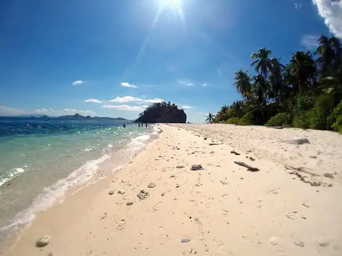 Pristine beach with white sand, turquoise waters, and palm trees in the Philippines. Perfect for travel and relaxation.