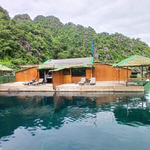 Beautiful floating house in clear blue waters surrounded by lush greenery in Palawan, Philippines.