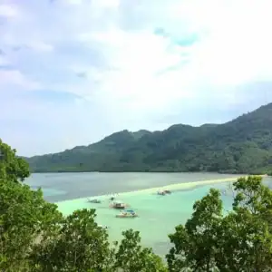 Scenic island view with turquoise waters and lush green mountains.