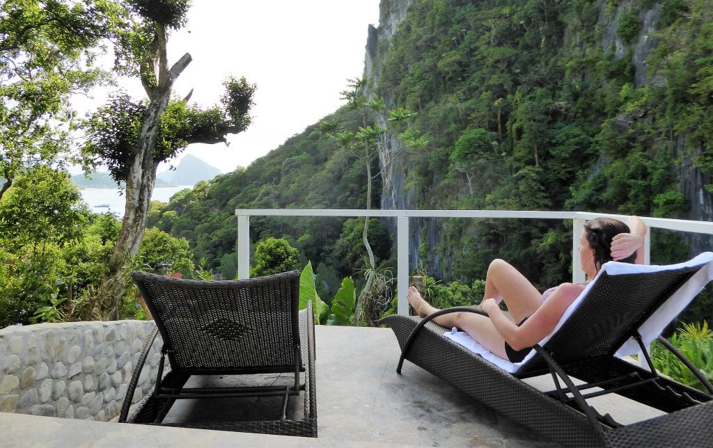 A woman lounging on a balcony overlooking lush green mountains in Philippines, enjoying scenic outdoor views.