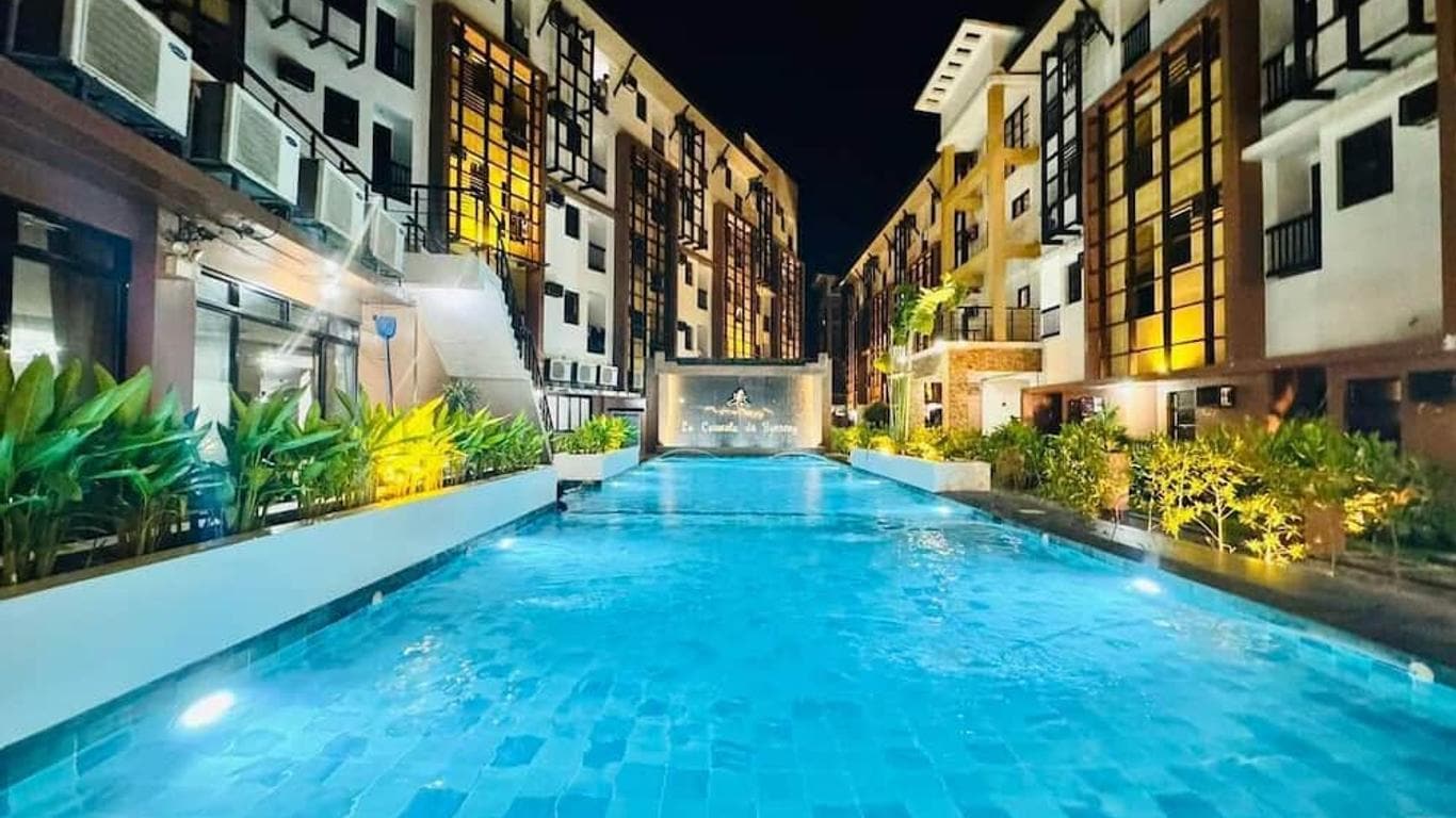 Night view of a modern hotel swimming pool with lush greenery in the Philippines.