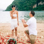 Romantic proposal on the beach in El Nido, Philippines, with a couple surrounded by candles and rose.