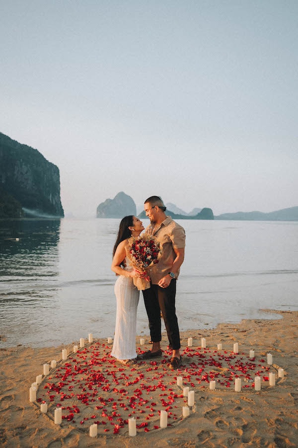 Romantic wedding proposal at El Nido beach with a heart-shaped arrangement of candles and rose petal.