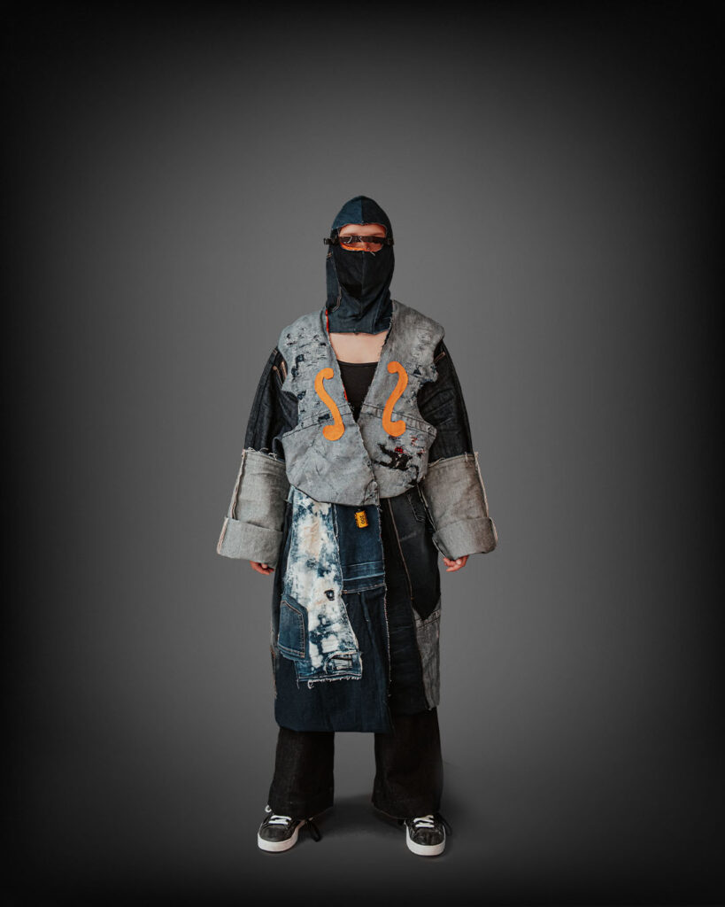 a person wearing a black mask and a coat