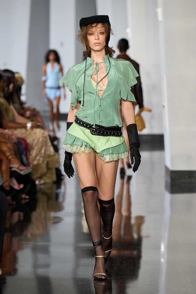 a model walks down the runway in a green outfit