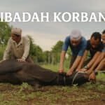 Sekumpulan lelaki Muslim sedang melaksanakan ibadah korban, menyembelih seekor lembu di kawasan lapang, berlatarbelakangkan alam semula jadi.