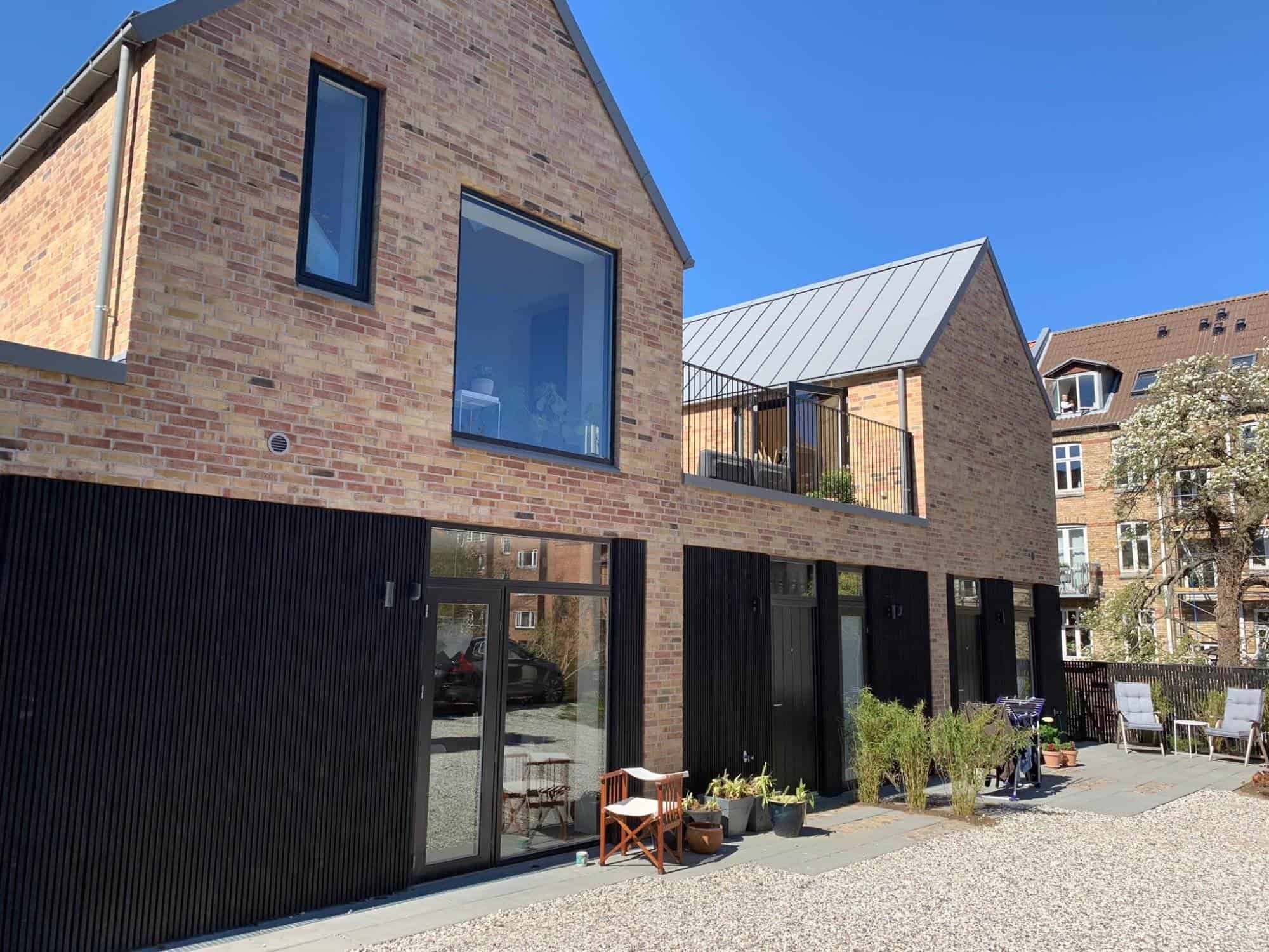 Moderne boligbyggeri med træfacade og store vinduer, skabt af Jakob Tømrerfirma A/S.