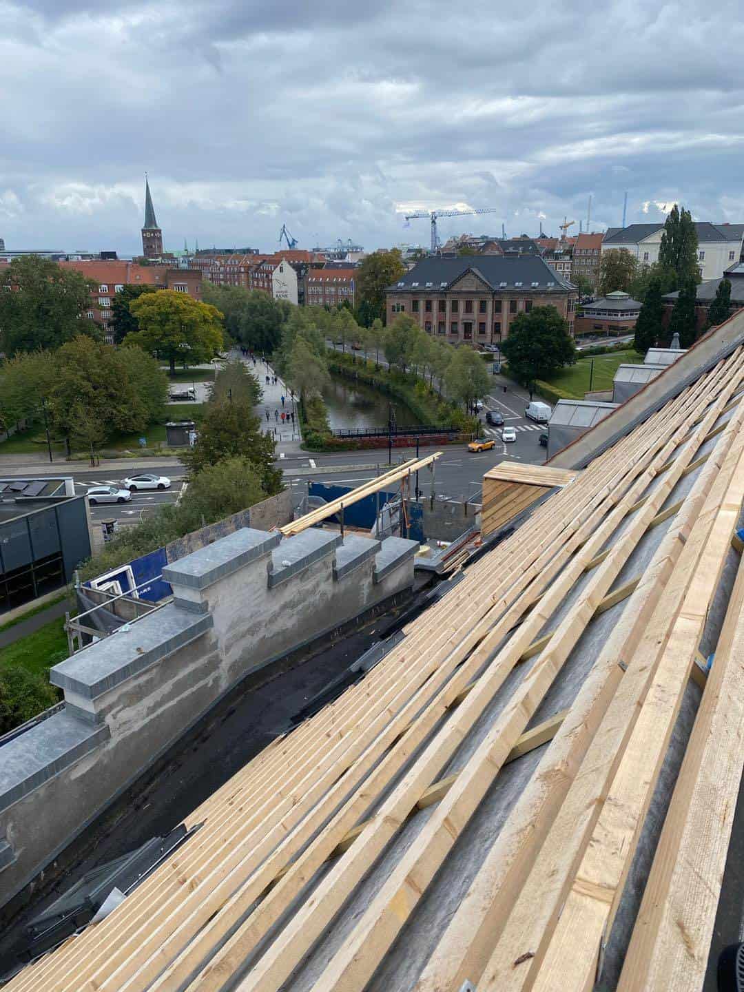 Nyt tag under renovering på en ejendom midt i Aarhus med byens skyline i baggrunden.