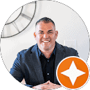 Modern real estate professional smiling in office, representing Jeff Brick &mdash; REALTOR, with a friendly and approachable demeanor.