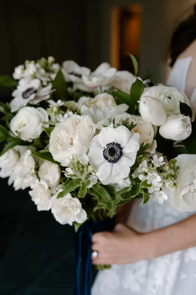 bride with navy ribbon, garden roses, stock, anemones, and tulips wedding bouquet by organic elements