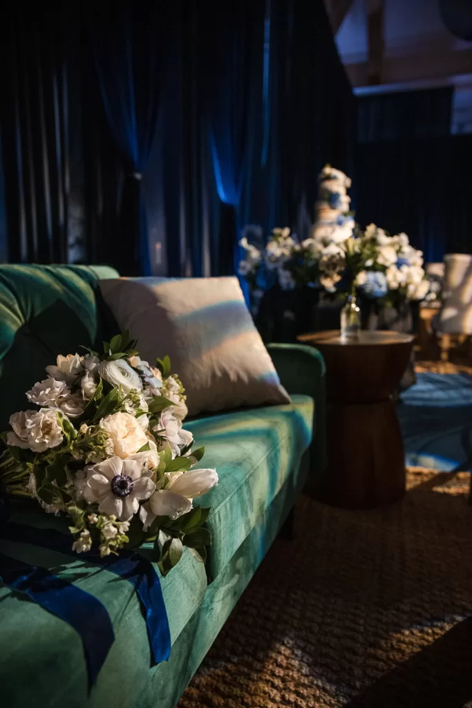 Southpointe ballroom floral installation of white garden roses and anemones set on a green velvet couch with filtered lighting