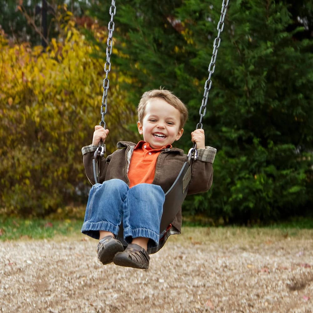 young child smiling on swing