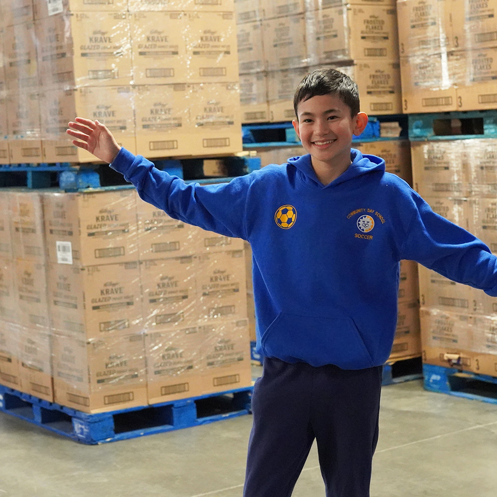 Ender Lin standing in front of 43 pallets of donated cereal-Photo by Greater Pittsburgh Community Food Bank